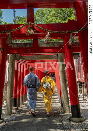 A foreign couple in yukata strolling through a shrine lined with torii gates A foreign couple in yukata strolling through a shrine lined with torii gates 117945992