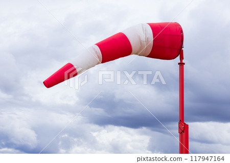 Red and white weather vane and dramatic cloudy sky. Red and white weather vane and dramatic cloudy sky. 117947164