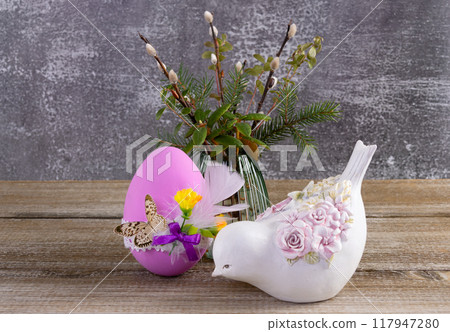 Easter decorated egg, pussywillow and a figurine of bird on the table. 117947280