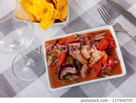 Fish ceviche and bowl of fried plantains chips are served in beautiful ceramic dishes 117948795
