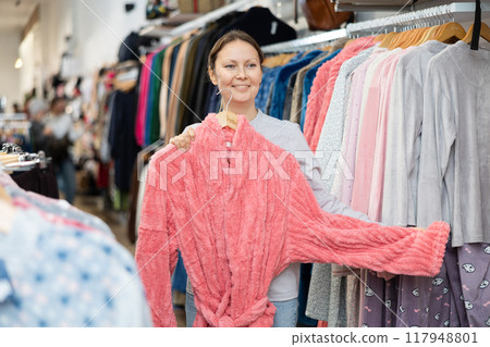 Middle-aged woman choosing convenient bathrobe in clothing store 117948801