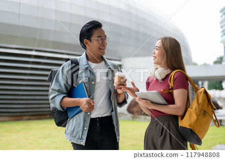 Two cheerful Asian college students are enjoying a conversation while walking together. 117948808