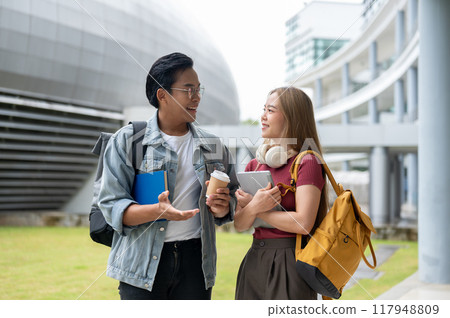 Two cheerful Asian college students are enjoying a conversation while walking together. Two cheerful Asian college students are enjoying a conversation while walking together. 117948809