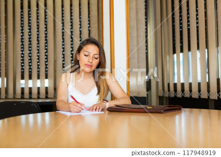 Positive latin american woman signing documents 117948919