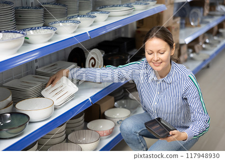 Woman choosing square ceramic plates on shelves at Asian store Woman choosing square ceramic plates on shelves at Asian store 117948930
