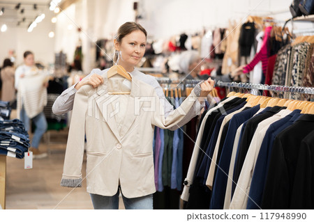 Middle-aged woman choosing convenient blazer in clothing store 117948990