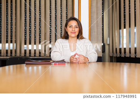 Young latin american businesswoman sitting with briefcase in meeting room 117948991