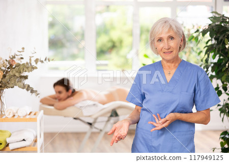 Elderly woman masseuse posing in spa salon Elderly woman masseuse posing in spa salon 117949125