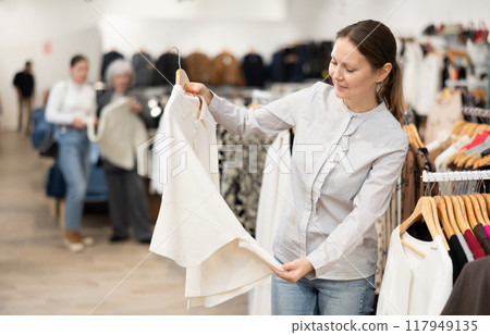 Adult woman choosing coat in store 117949135