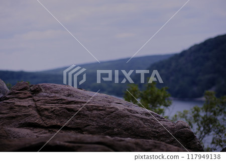 Rock cliff overlooking a lake and hills Rock cliff overlooking a lake and hills 117949138