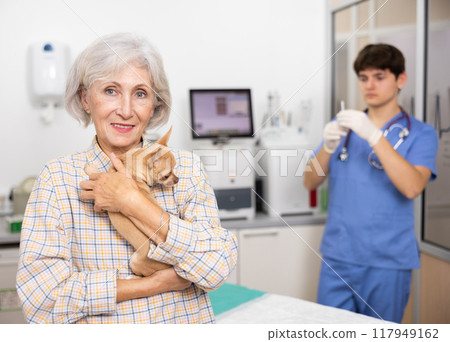Smiling aged woman bringing chihuahua to veterinary clinic for routine checkup Smiling aged woman bringing chihuahua to veterinary clinic for routine checkup 117949162
