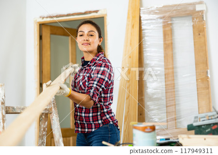 Woman carrying wooden planks in new apartment 117949311