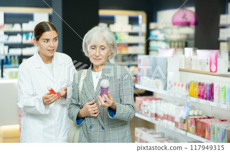 Mature lady choosing lubricant with help of young female pharmacist Mature lady choosing lubricant with help of young female pharmacist 117949315