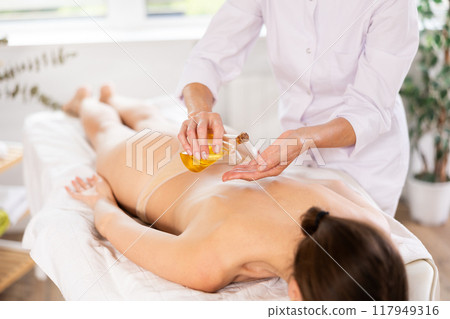 Masseuse giving oil massage to young woman 117949316