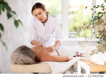 Young woman doing back massage to elderly woman Young woman doing back massage to elderly woman 117949348