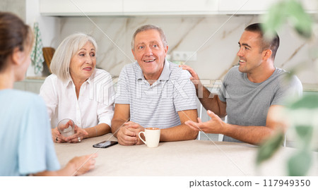 Family of four sits at table and talking Family of four sits at table and talking 117949350