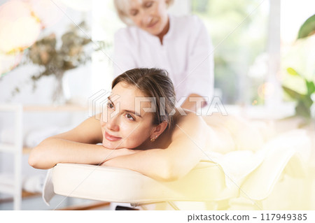 Young woman enjoying relaxing massage from professional female masseur 117949385