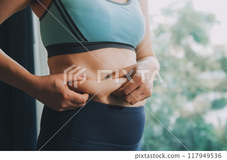 fat woman, fat belly, chubby, obese woman hand holding excessive belly fat with measure tape, woman diet lifestyle concept 117949536