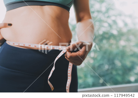 fat woman, fat belly, chubby, obese woman hand holding excessive belly fat with measure tape, woman diet lifestyle concept 117949542