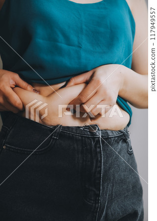 fat woman, fat belly, chubby, obese woman hand holding excessive belly fat with measure tape, woman diet lifestyle concept 117949557