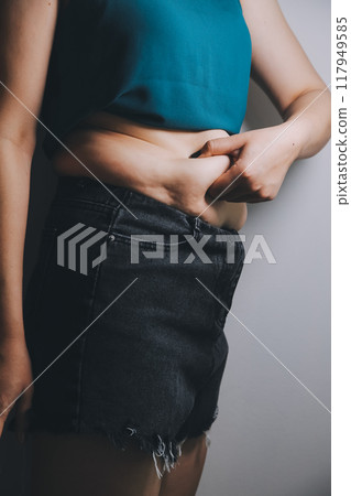 fat woman, fat belly, chubby, obese woman hand holding excessive belly fat with measure tape, woman diet lifestyle concept 117949585