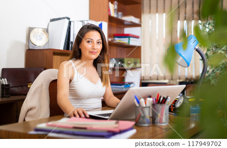 Concentrated young adult woman working at office 117949702