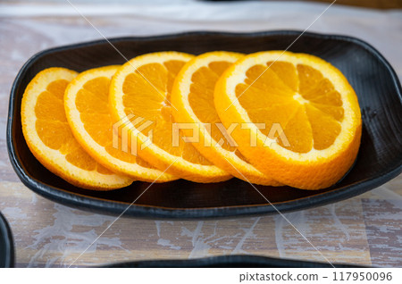Sliced orange on a plate 117950096