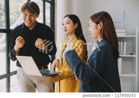 Group of Young Asian business team creative businesspeople coworker in office Happy to be successful partnership teamwork celebrating achievement and success concept. 117950253