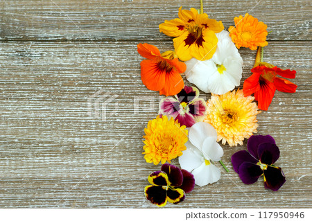 Wooden brown table with edible flowers (nasturtium, calendula, pansy) on the side. Wooden brown table with edible flowers (nasturtium, calendula, pansy) on the side. 117950946