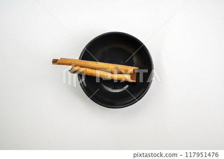 A bowl of cinnamon sticks sits on a white background 117951476