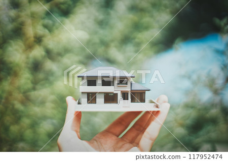 持有房屋模型的人的手和綠色模糊背景 117952474