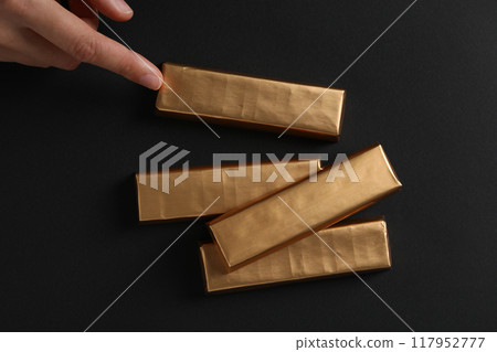 Chocolate bars in gold foil on a dark background Chocolate bars in gold foil on a dark background 117952777