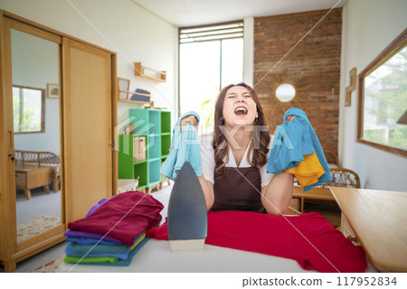 An Indonesian housewife is in a room with a pile of clothes and a pile of towels An Indonesian housewife is in a room with a pile of clothes and a pile of towels 117952834