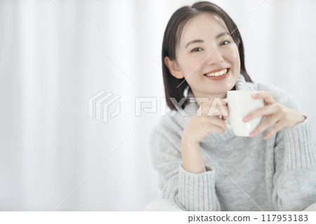 Young woman in sweater holding a mug Young woman in sweater holding a mug 117953183