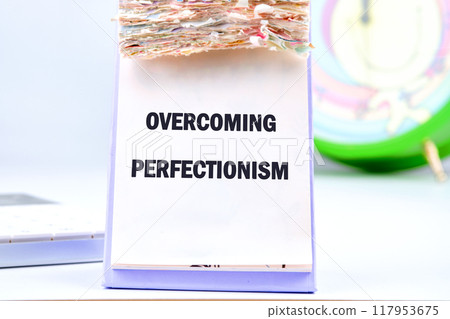 Business Overcoming perfectionism concept. Copy space. Concept words Overcoming perfectionism in a desktop calendar on a light background Business Overcoming perfectionism concept. Copy space. Concept words Overcoming perfectionism in a desktop calendar on a light background 117953675