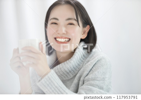 Young woman in sweater holding a mug Young woman in sweater holding a mug 117953791