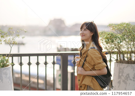 Traveler young asian woman 30s in express boat pier on the Chao Phraya River in Bangkok. Journey trip lifestyle, world travel explorer or Asia summer tourism concept. Traveler young asian woman 30s in express boat pier on the Chao Phraya River in Bangkok. Journey trip lifestyle, world travel explorer or Asia summer tourism concept. 117954657