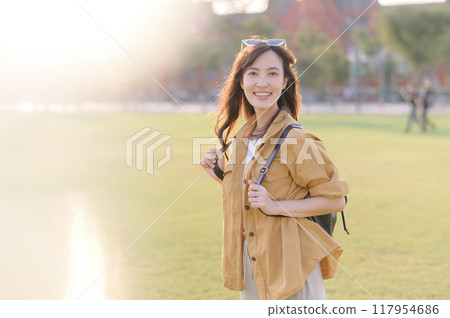 Traveler asian woman in her 30s stands bathed in the golden glow of sunset, embracing the freedom of exploration. on summer holiday weekend vacation trip in Bangkok, Thailand 117954686