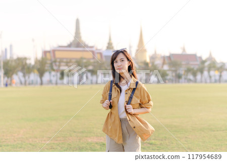 A Traveler Asian woman in her 30s exploring Wat Pra Kaew. From stunning architecture to friendly locals, she cherishes every moment, capturing it all in her heart and camera for years to come. 117954689