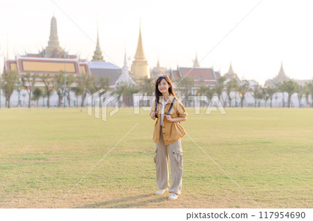 A Traveler Asian woman in her 30s exploring Wat Pra Kaew. From stunning architecture to friendly locals, she cherishes every moment, capturing it all in her heart and camera for years to come. 117954690