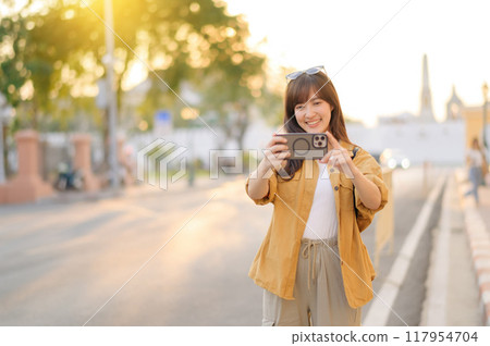 Traveler asian woman in her 30s using smartphone to take a photo while traveling urban street in Bangkok, Thailand Traveler asian woman in her 30s using smartphone to take a photo while traveling urban street in Bangkok, Thailand 117954704