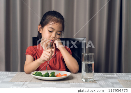 Little cute kid girl refusing to eat healthy vegetables. Children do not like to eat vegetables. Little cute kid girl refusing to eat healthy vegetables. Children do not like to eat vegetables. 117954775