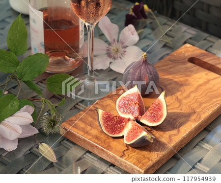 Peeled and cut fresh figs with rose wine on terrace sunny day. Food and drink of Mediterranean. Summer and vacation.  117954939