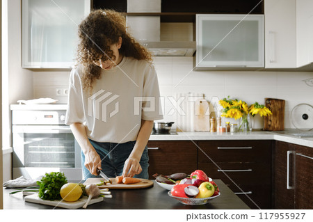 Woman chopping carrot in the kitchen 117955927