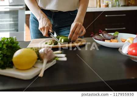 Close-up of female hands chopping fresh baby zucchini Close-up of female hands chopping fresh baby zucchini 117955930
