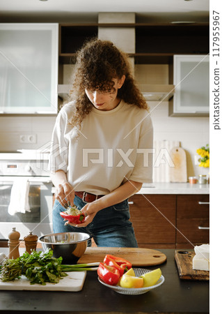 Woman stuffing bell peppers with grated cheese 117955967