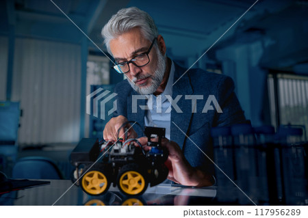 Automation, robotics engineer assembling robotic car prototype for delivery, warehouse. Concept of modern technology in industries, automated processes, automotive 117956289