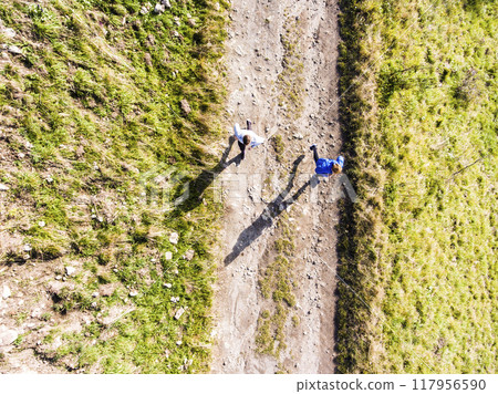 Aerial view of two runners jogging on dirt running trail in nature. Morning running training for friends. Aerial view of two runners jogging on dirt running trail in nature. Morning running training for friends. 117956590