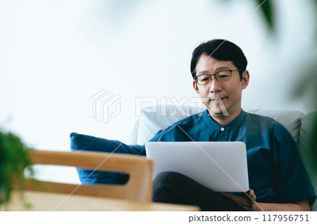 A man using a computer in the living room A man using a computer in the living room 117956751