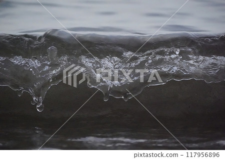 White foam and sea water drop splashes slow motion with sand and blue water 117956896